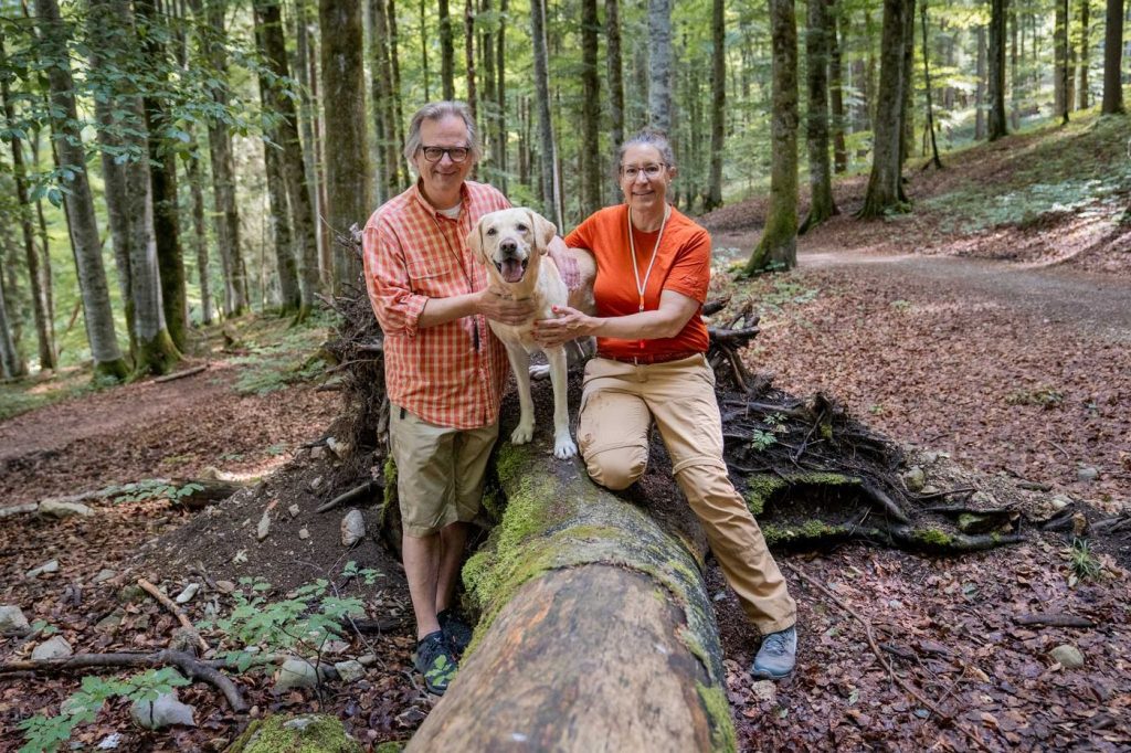 Pause am Baumstamm: Teilnehmende mit ihrem Hund beim Social Walk
